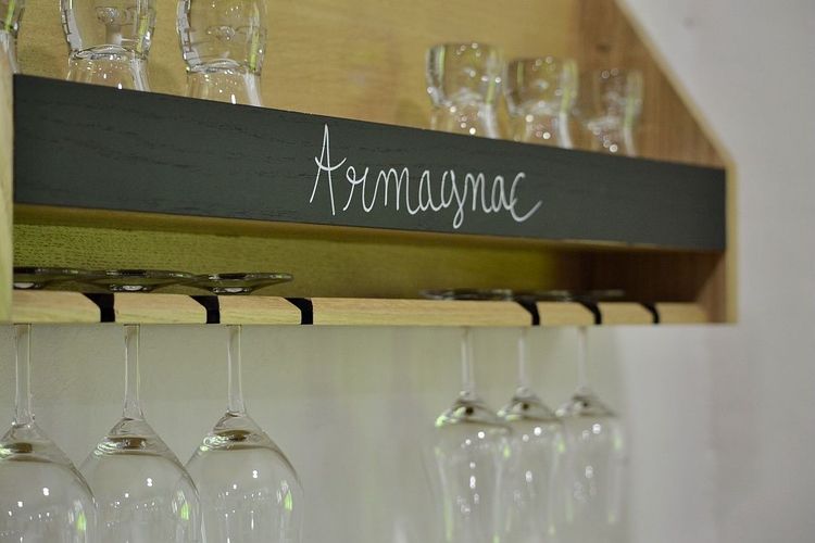 Un présentoir avec des verres suspendus, et le mot Armagnac sur un écriteau au-dessus